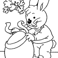 Desenho de Coelho colocando laço no ovo de Páscoa para colorir